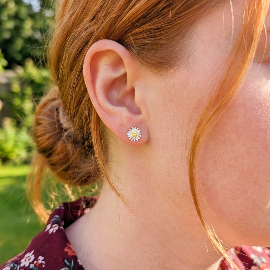A woman outside wearing little daisy silver stud earrings