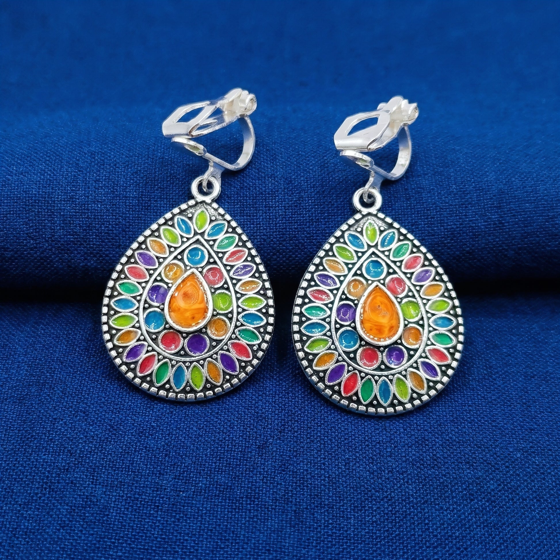 Colorful silver mandala boho clip-on earrings on a blue background