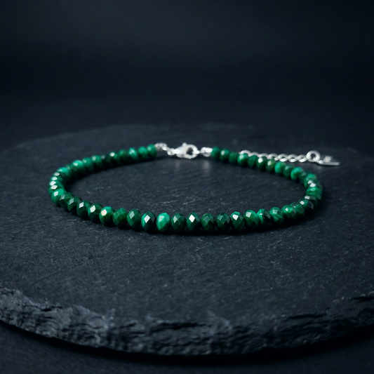 Natural green malachite bead bracelet with a 925 silver clasp on a dark stone background