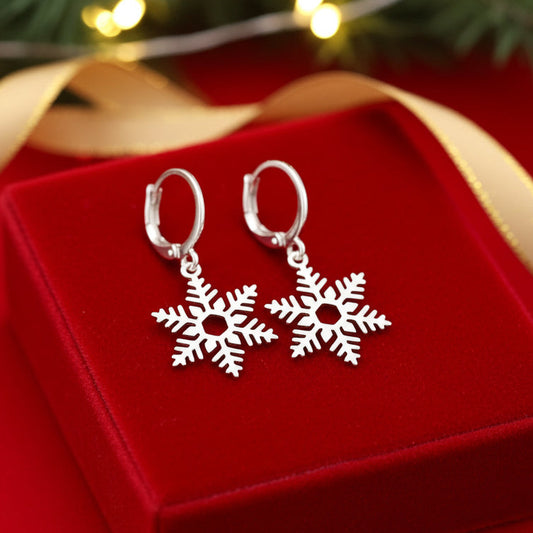 Silver snowflake hoop earrings on a red velvet box with Christmas lights in the background