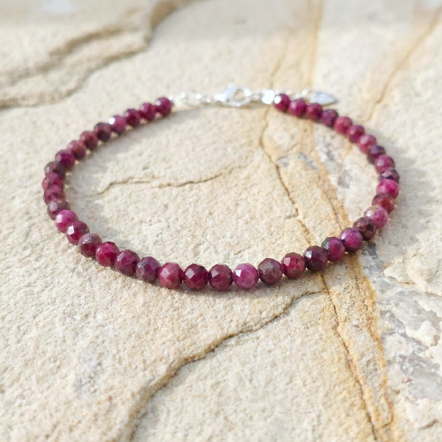 Natural ruby bracelet with silver clasp on a stone surface