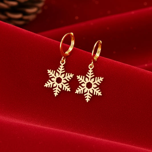 Gold snowflake earrings on a red fabric background