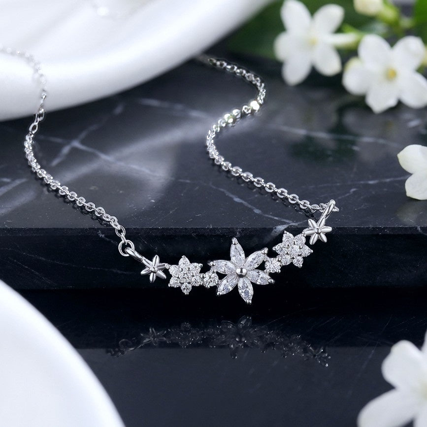 Dainty flower pendant made with 925 sterling silver and sparkly crystals, on a black marble background