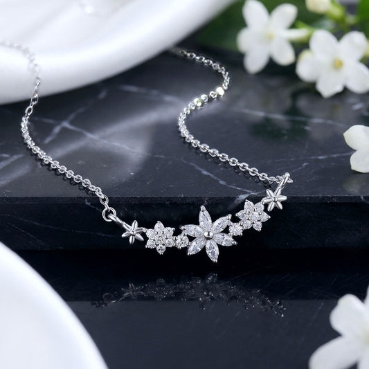 Dainty flower pendant made with 925 sterling silver and sparkly crystals, on a black marble background