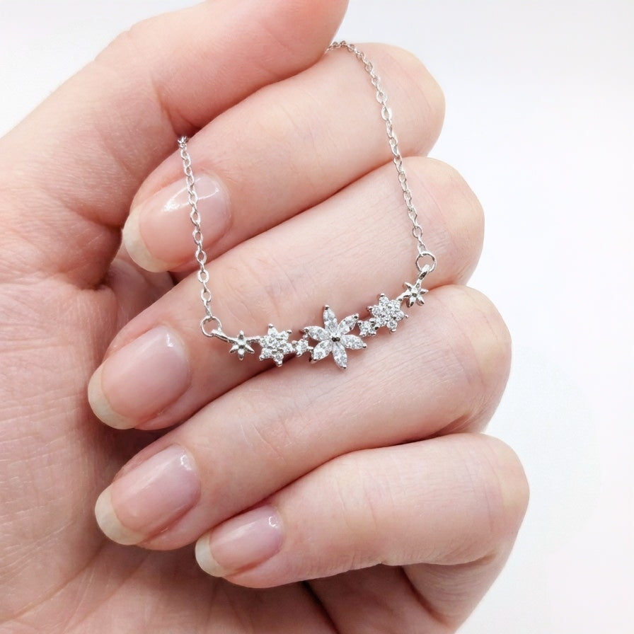 A hand holding a delicate flower necklace