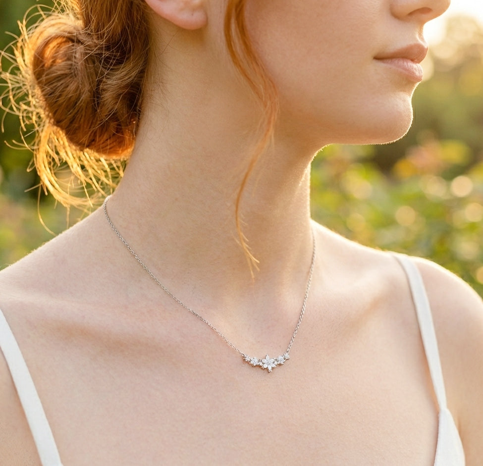 A woman in the sunshine wearing a dainty flower necklace made with 925 sterling silver