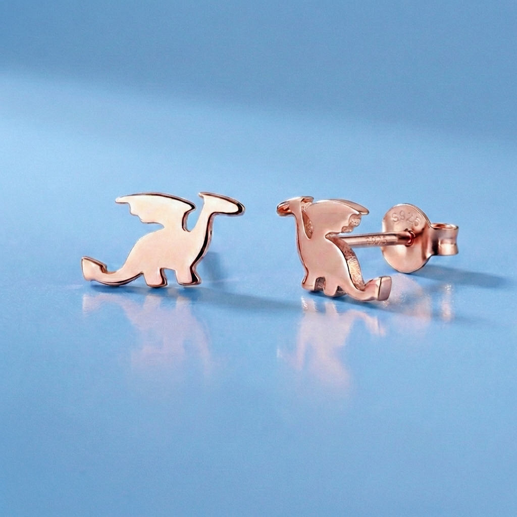 Rose gold dragon earrings on a light blue background. there is a 925 stamped on the earrings