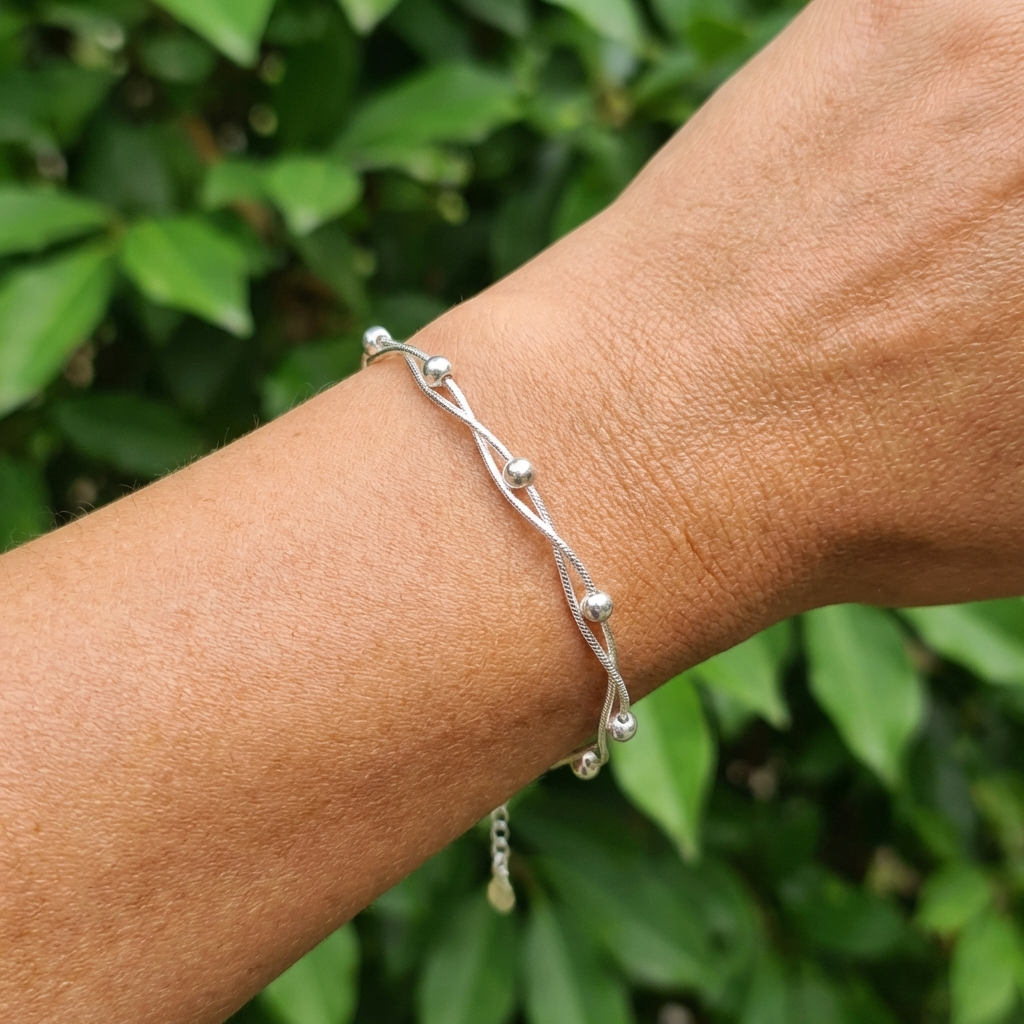 A wrist wearings a 925 Silver Bracelet with two intertwined snake chains and round beads outside.