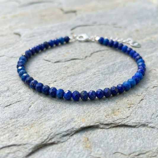 Blue lapis lazuli beaded bracelet with 925 silver clasp on a stone surface