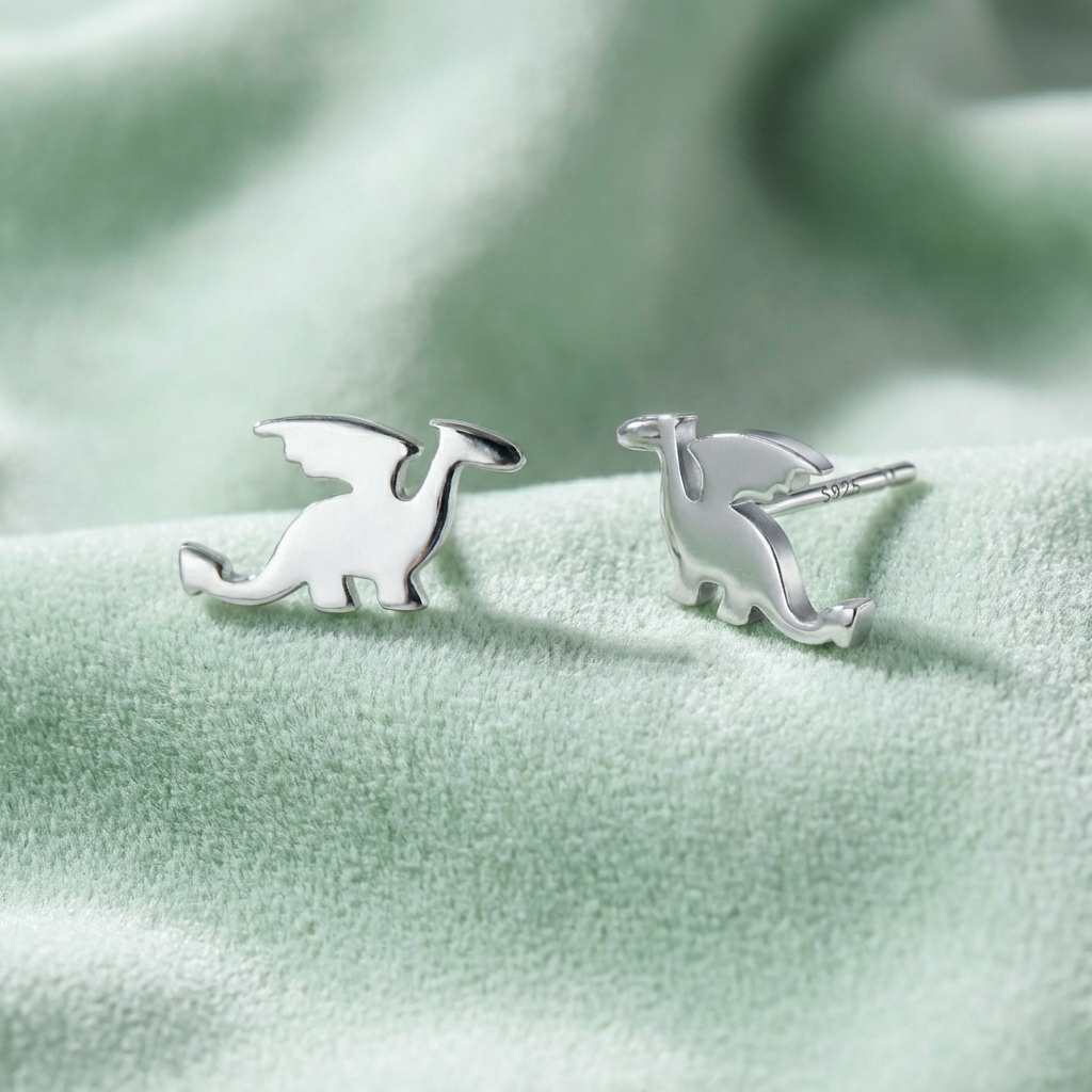 Silver dragon stud earrings on a light green fabric background. the earrings have 925 stamped on them