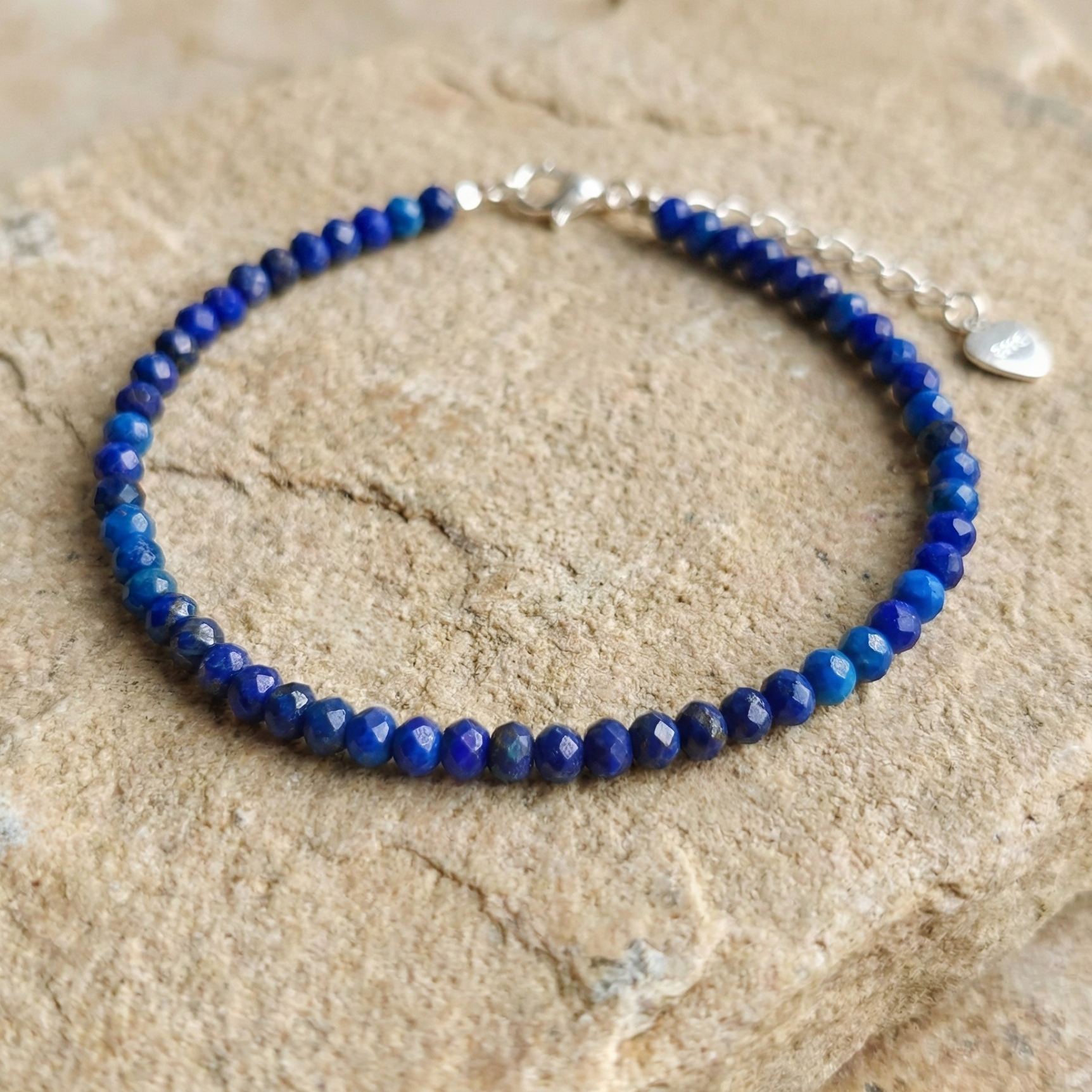 Blue lapis lazuli beaded bracelet with 925 silver clasp on a stone surface