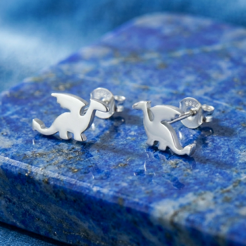 Silver dragon-shaped earrings on a blue stone surface
