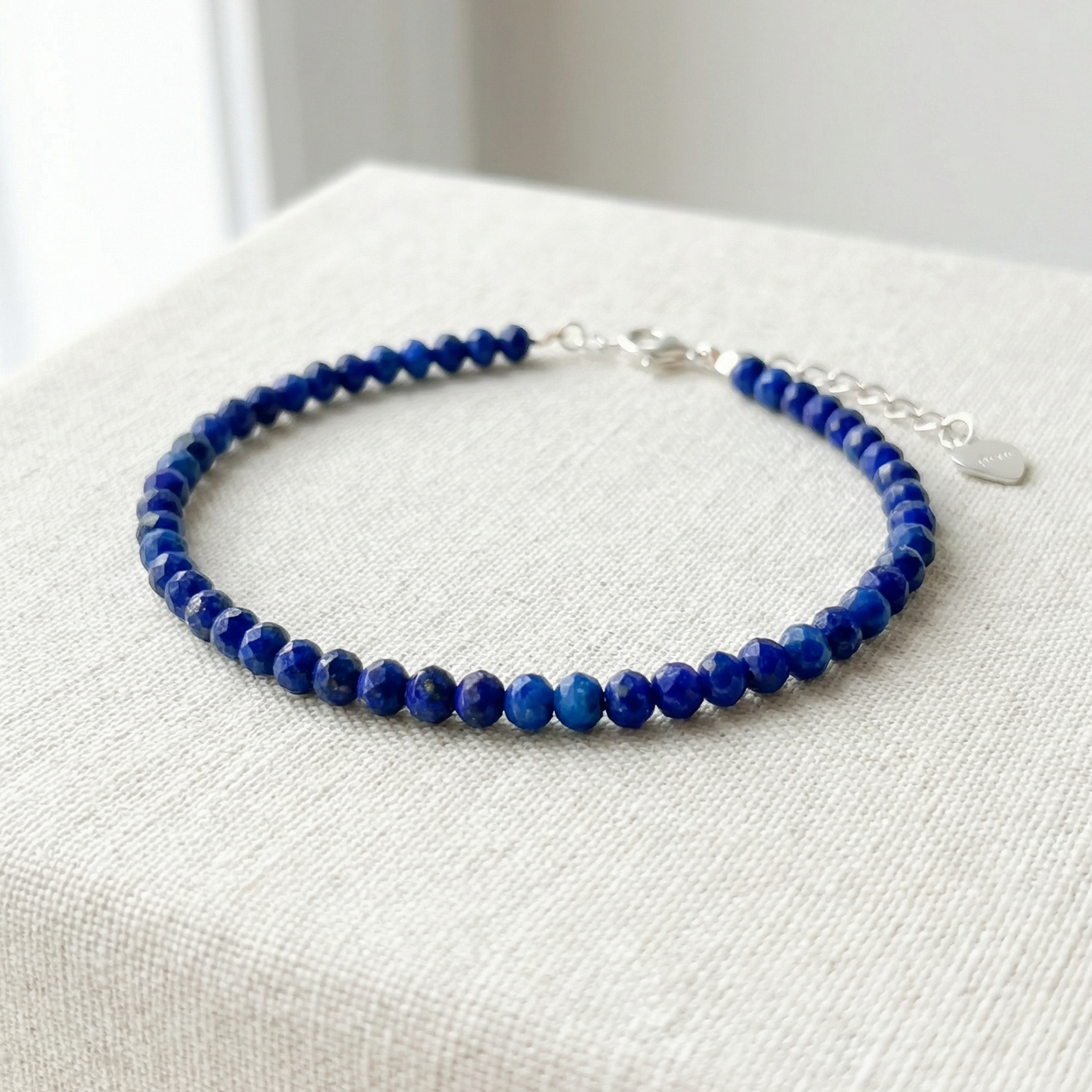 Blue lapis lazuli beaded bracelet with 925 silver clasp on a light material surface