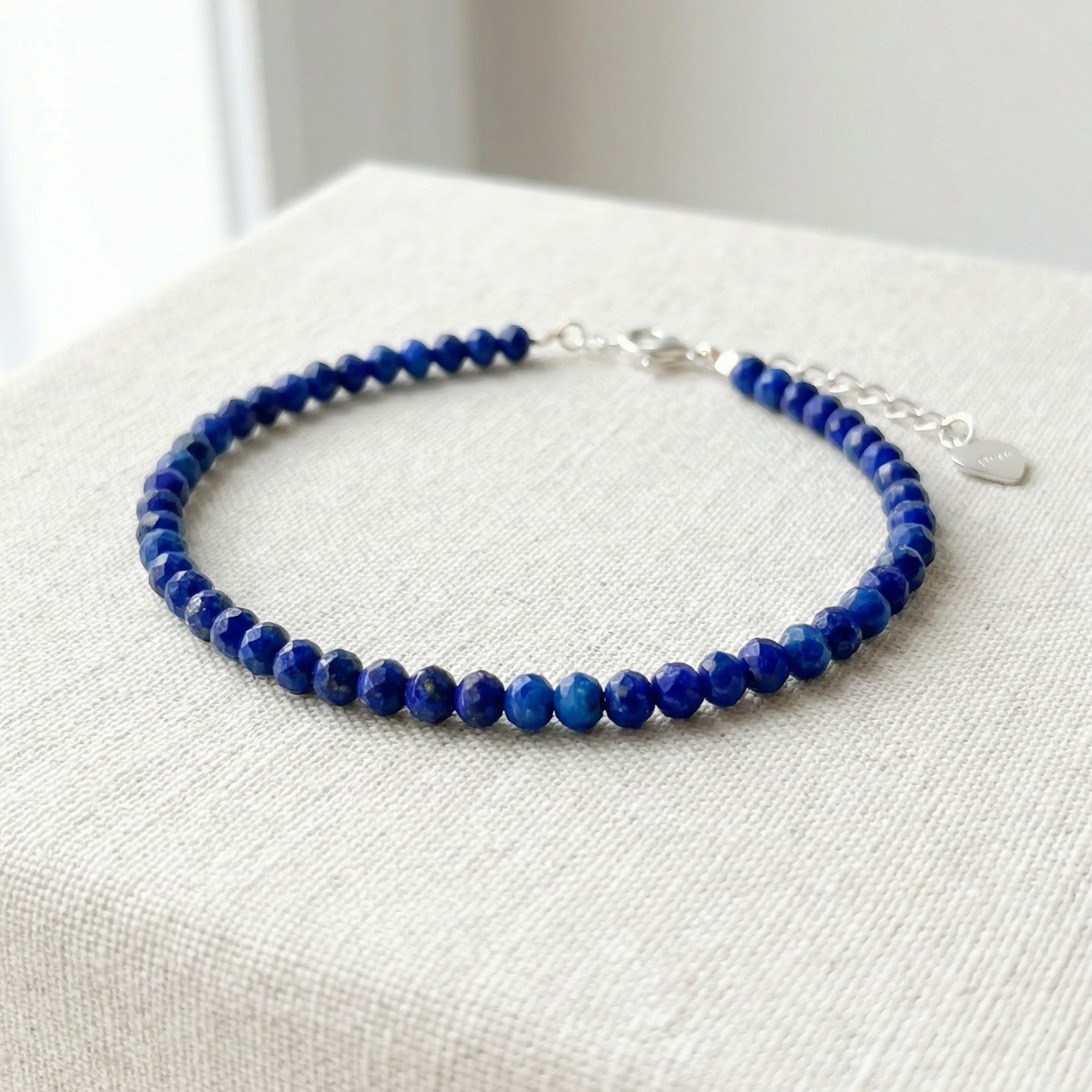 Blue lapis lazuli beaded bracelet with 925 silver clasp on a light material surface