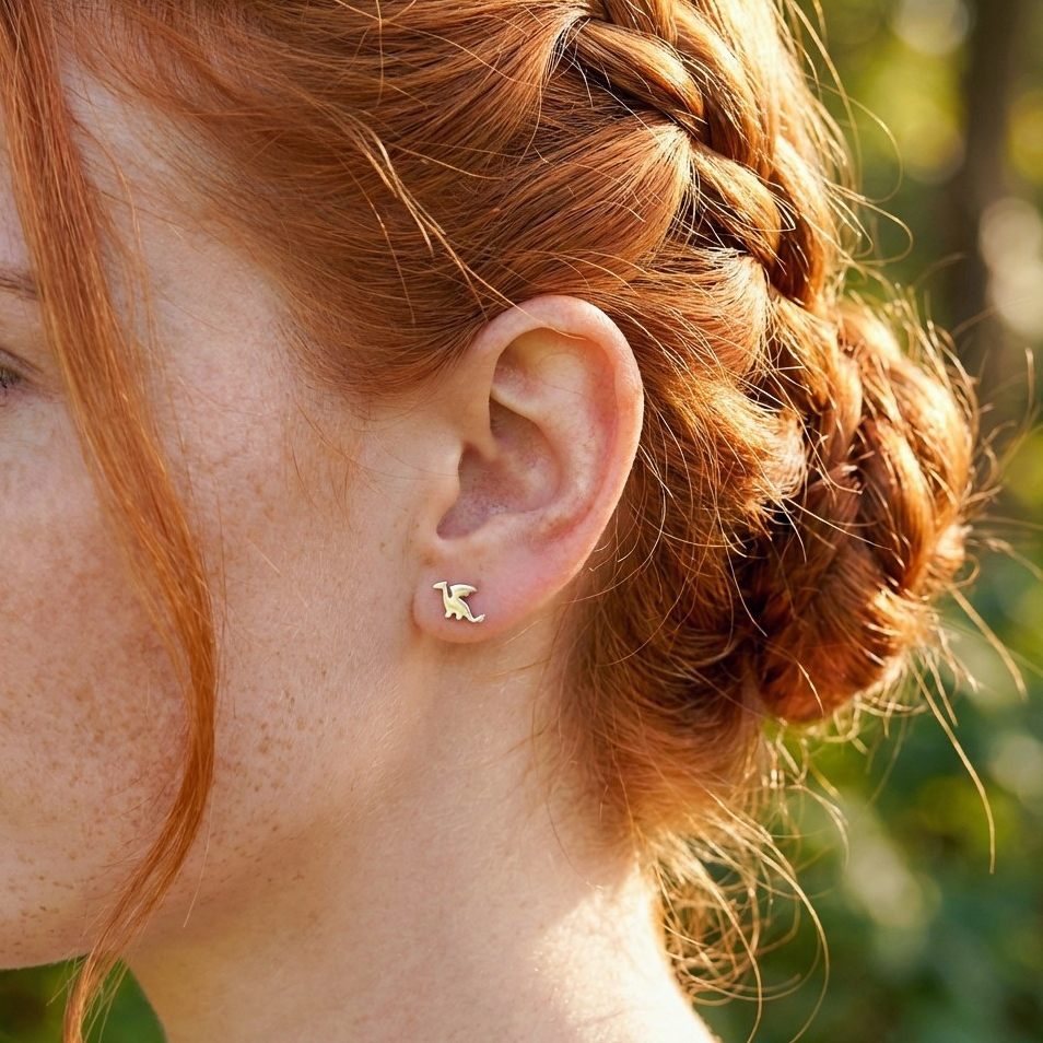 Close-up of a woman's ear with a silver dragon earring, red hair styled in a fantasy braid.