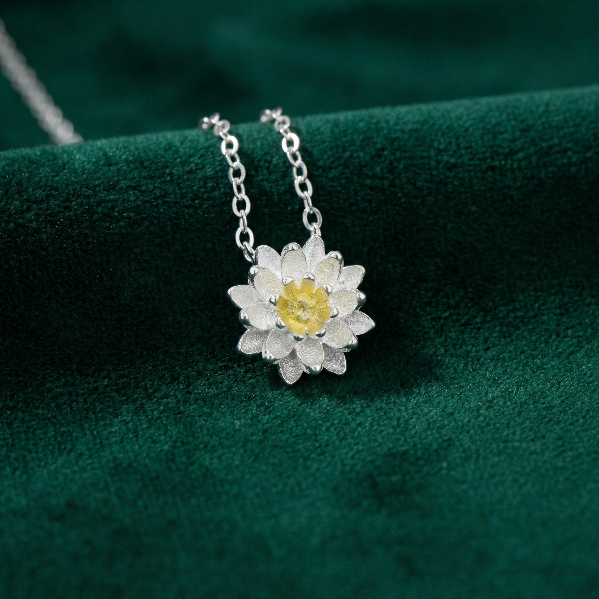 Silver necklace with a flower pendant on a green fabric background
