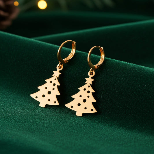 Festive Christmas tree earrings with hoops made from gold stainless steel on green velvet with lights in the background.