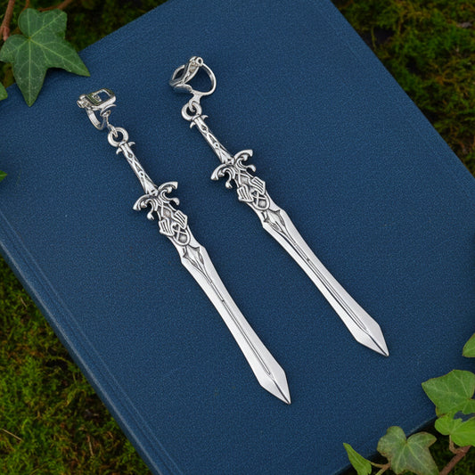 Silver sword clip on earrings on a blue surface with green leaves around