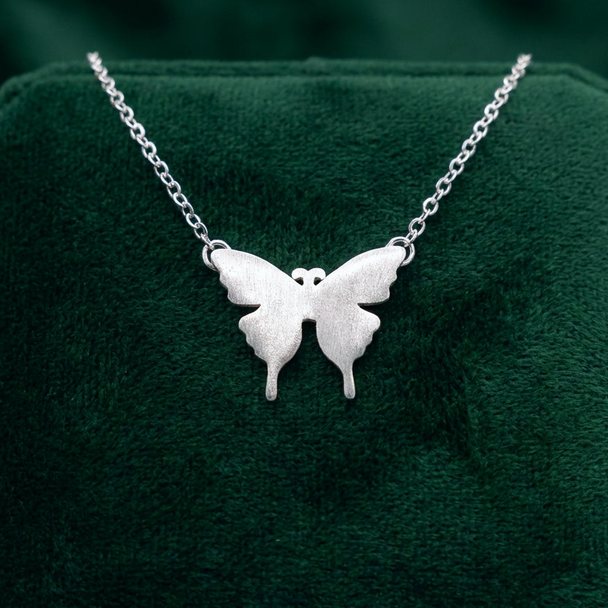 Silver butterfly necklace on a green cushion