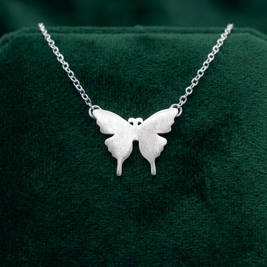 Silver butterfly necklace on a green cushion