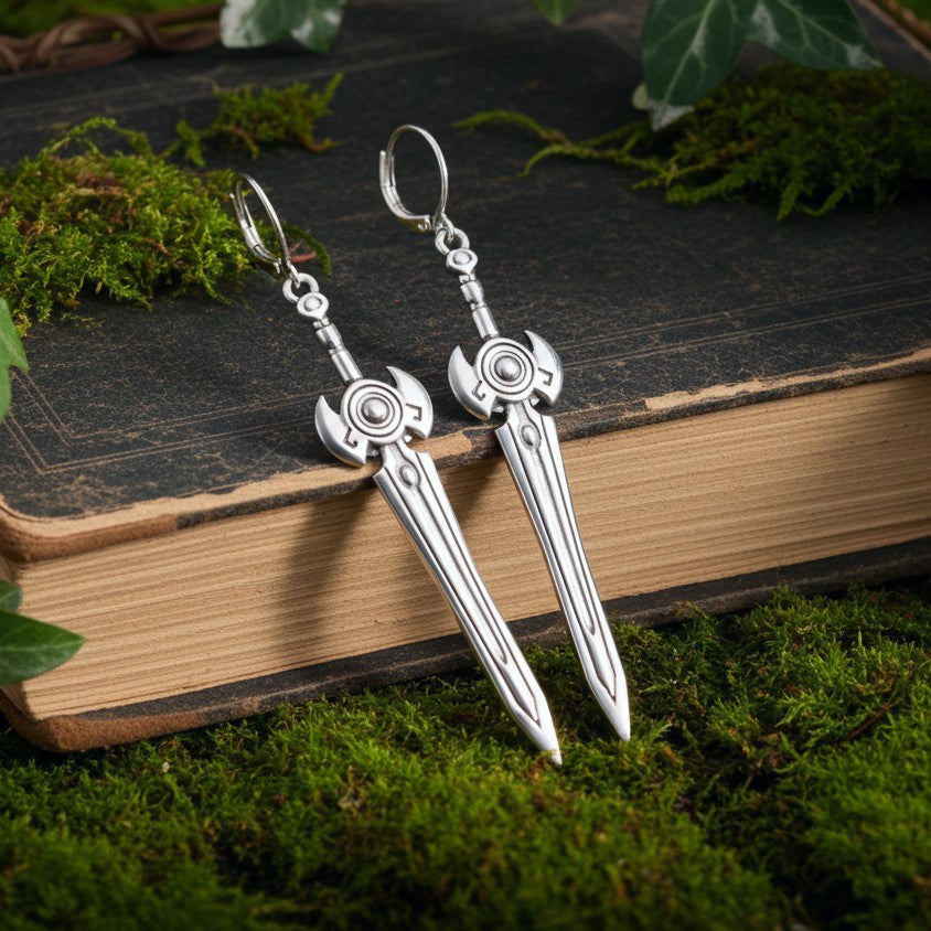 Sci fi fantasy silver sword earrings with hoops on a book with moss