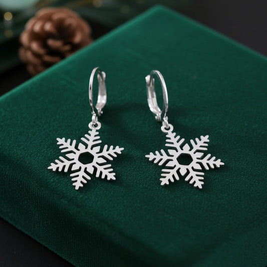 Silver snowflake earrings on a green fabric background
