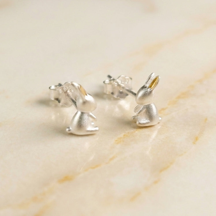 Silver rabbit-shaped earrings on a marble surface