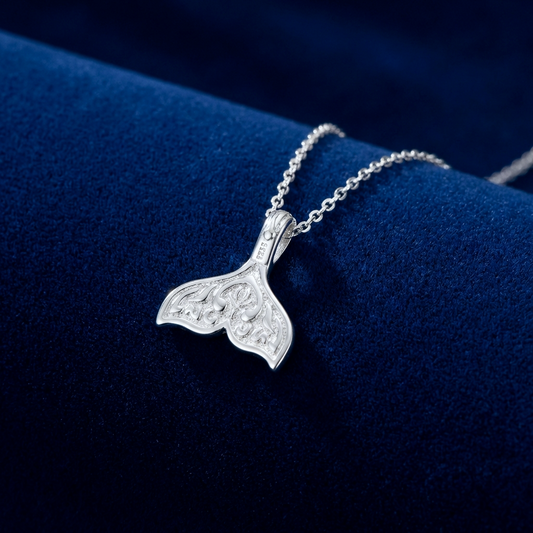 The back of a silver whale tail necklace, showing the S925 stamp, on a blue background