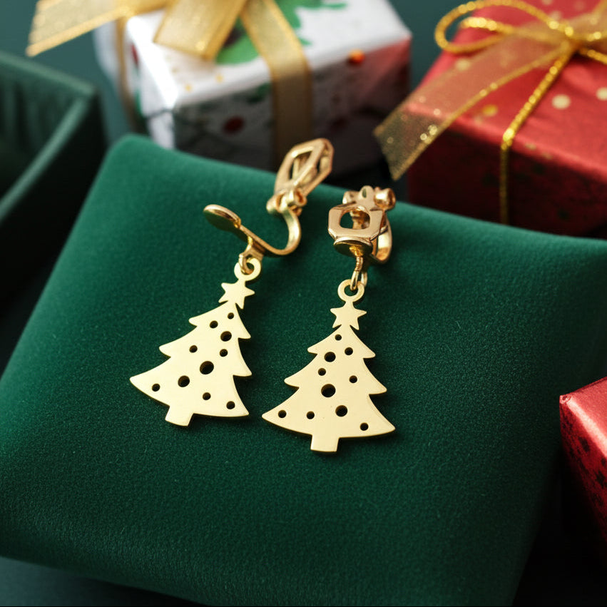 Festive Christmas tree earrings with clip-ons made from gold stainless steel on green velvet with presents in the background.