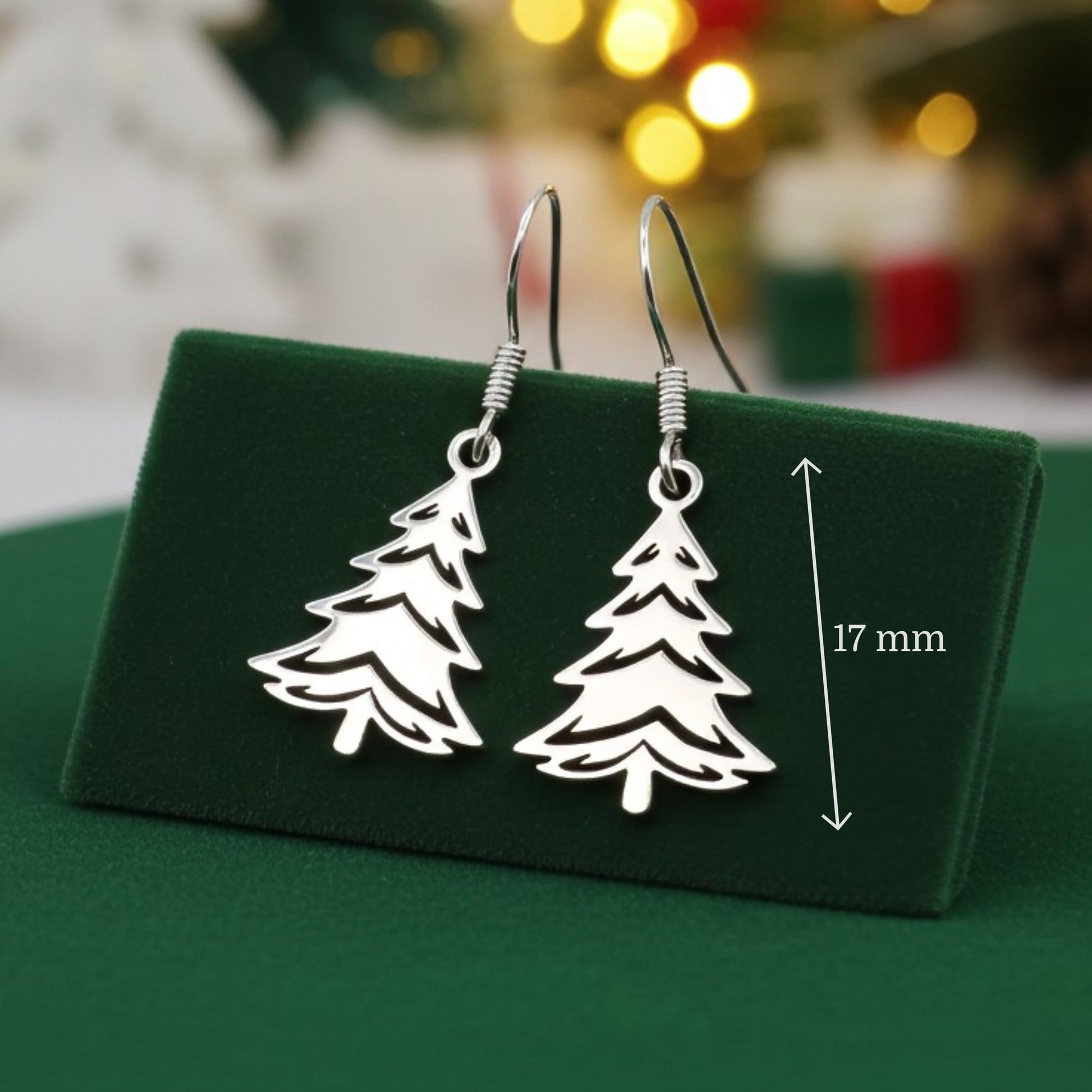 Silver Christmas tree earrings on a green stand with a festive background and the measurements shown