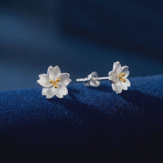 Video showing the silver flower stud earrings turning on a green background