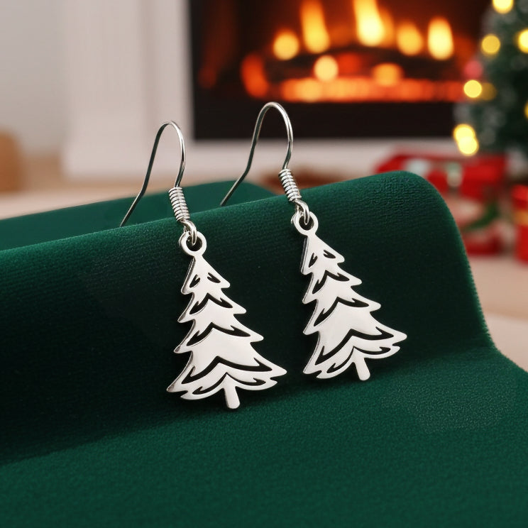 Silver Christmas tree earrings on a green stand with a festive background
